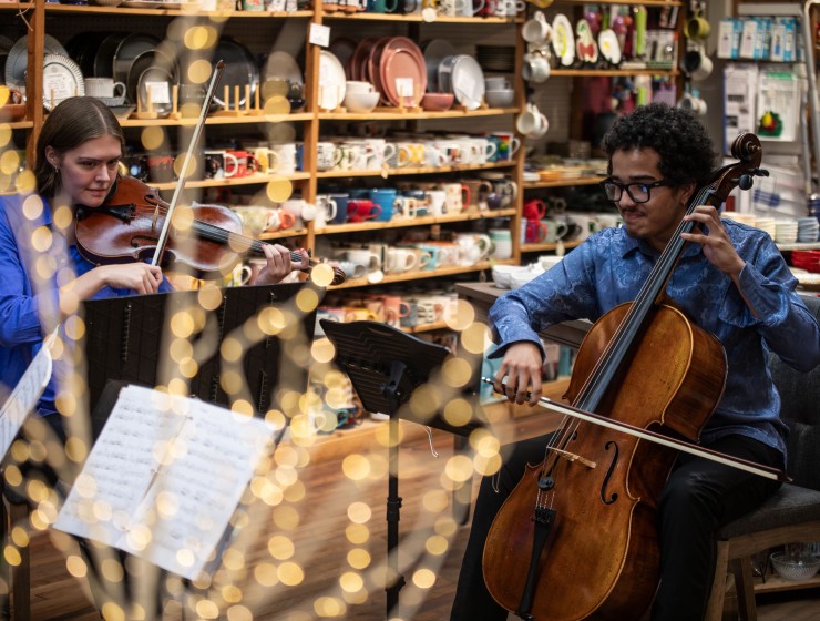 a cellist and a violist performing at a local home goods store with merchandise on shelves in the background