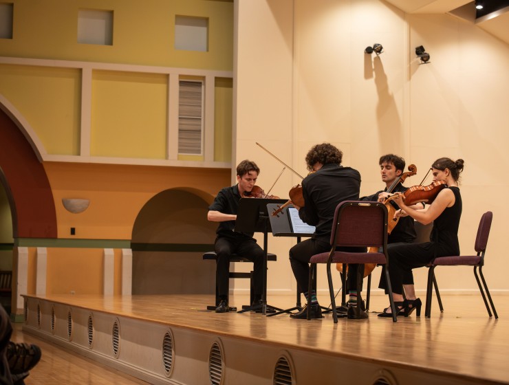 a string quartet performing on a concert stage, viewed from the side