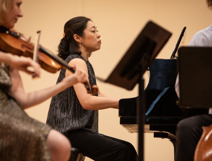 a pianist performing while her colleague is in the left foreground of the photo playing violin