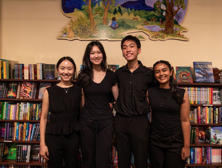 four students standing in a bookstore wearing all black