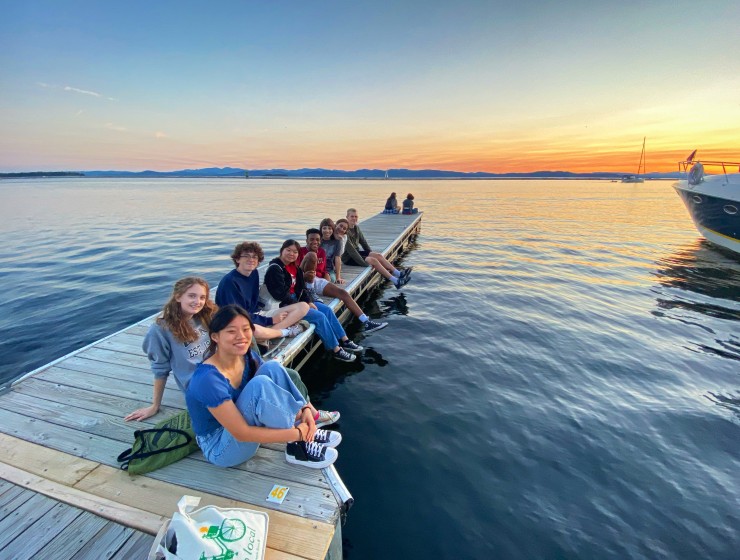 a group of students sitting on a dock at sunset
