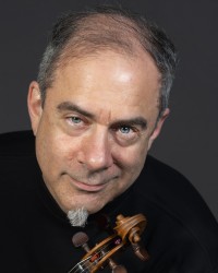 A man wearing a dark shirt holding a violin