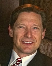 A close up photo of a man in a suit jacket with a white shirt and tie