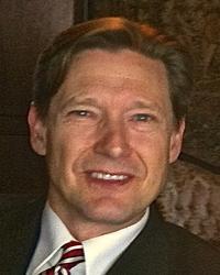 A close up photo of a man in a suit jacket with a white shirt and tie