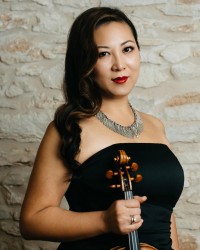 A woman wearing a black dress holding a violin