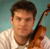 A headshot of a man with the violin close to his head on the right