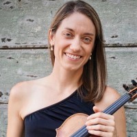 A woman with a one-shoulder black dress holding a violin