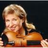 A woman smiling and holding a violin horizontally in front of her face